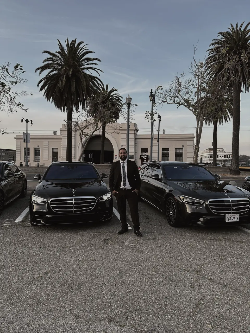 A BlackWingz chauffeur between 2 black Mercedes S-Class sedans
