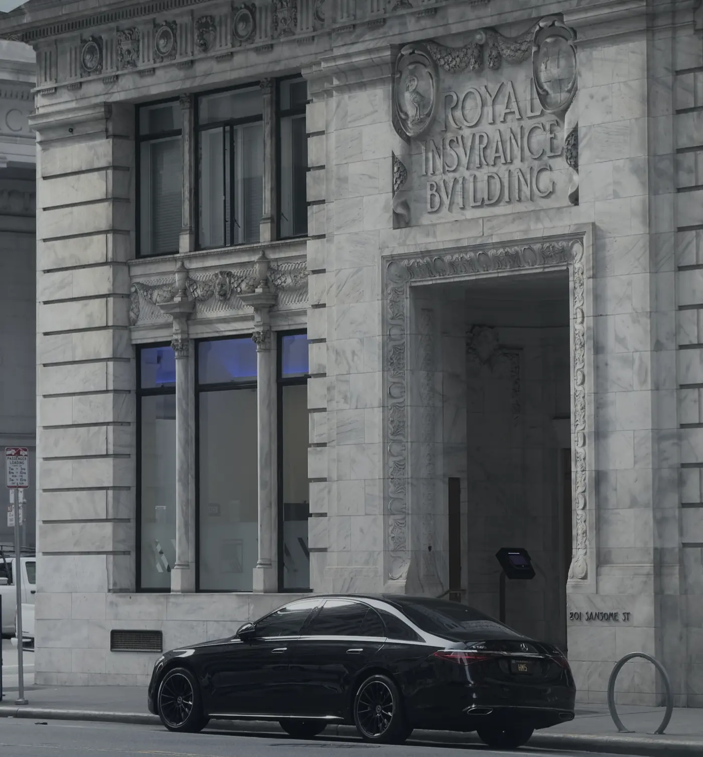 A black Mercedes S-Class outside a stone landmark building