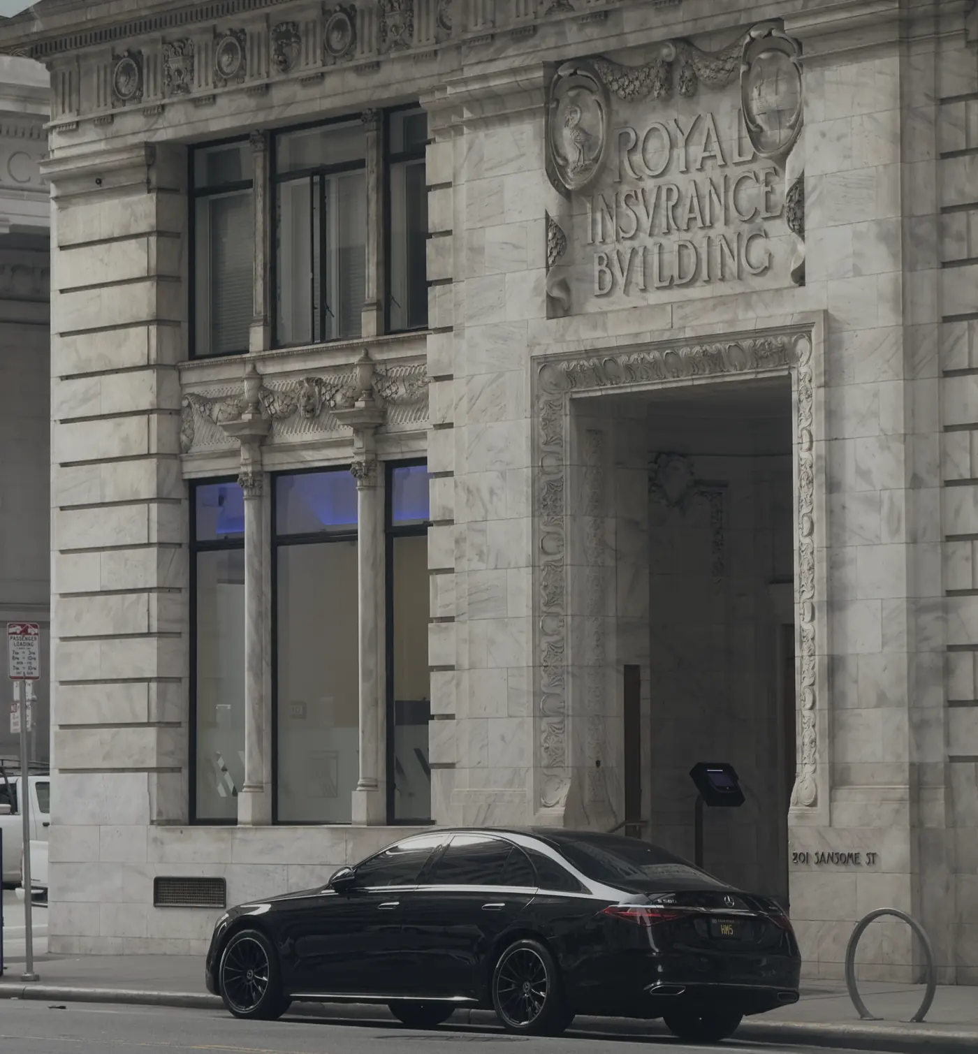 A black Mercedes S-Class outside a stone landmark building