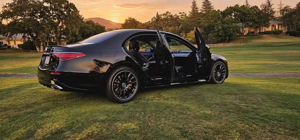 Mercedes S-Class with open doors beside a lawn