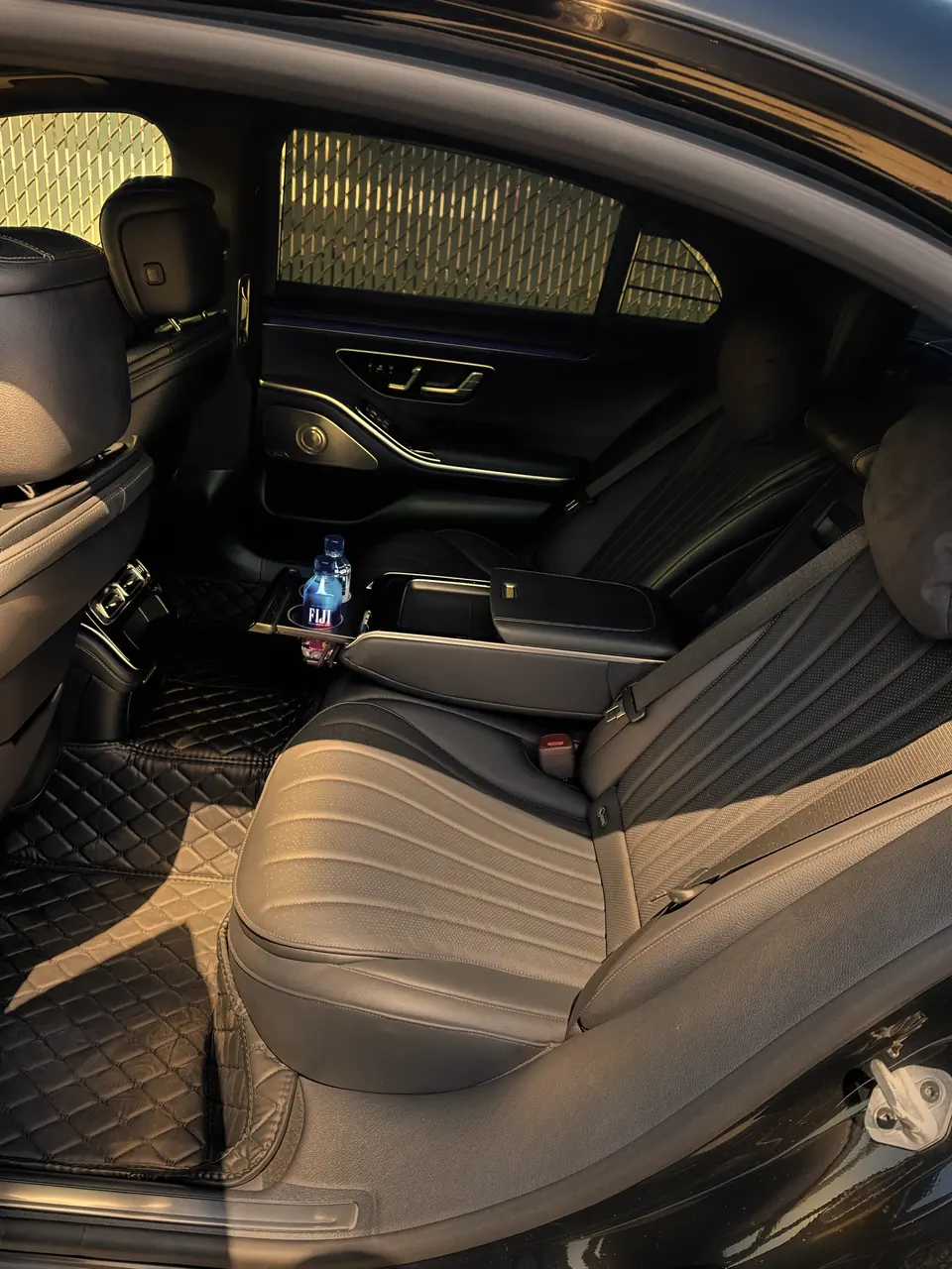 The rear seat of a Mercedes S-Class, with bottled water in the armrest