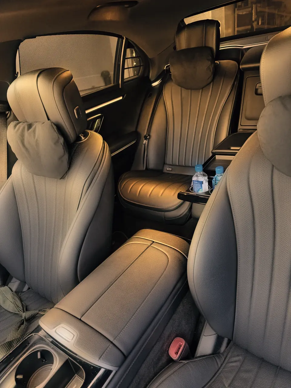 The rear seat of a Mercedes S-Class seen between the front seats, bottled water in the armrest