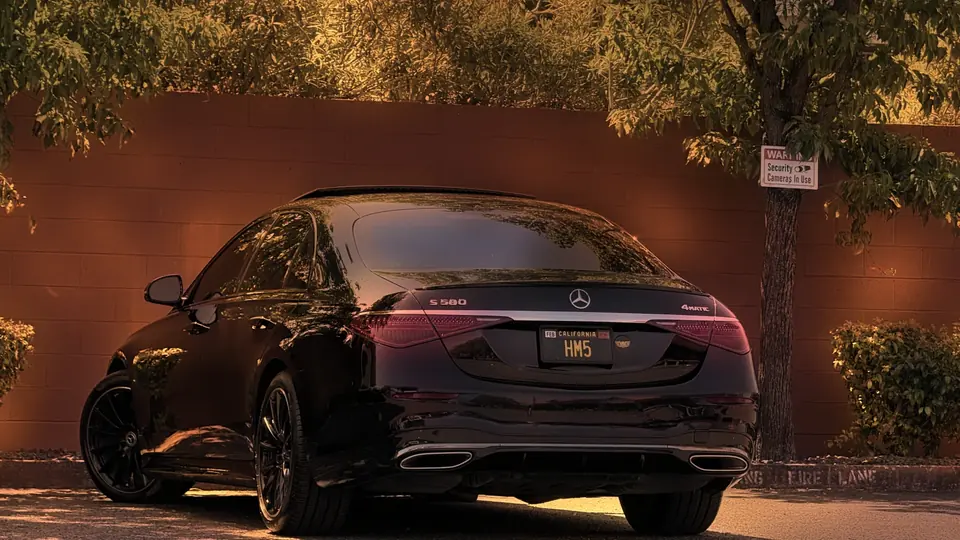 Rear view of a black Mercedes S-Class by a red wall