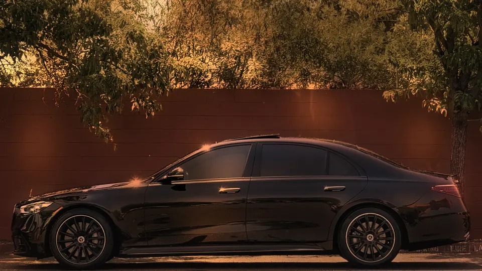 Side view of a black Mercedes S-Class by a red wall