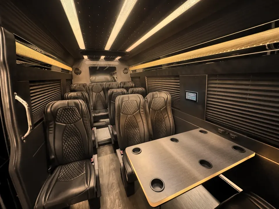 Rows of leather seats and a table inside a Mercedes Sprinter van