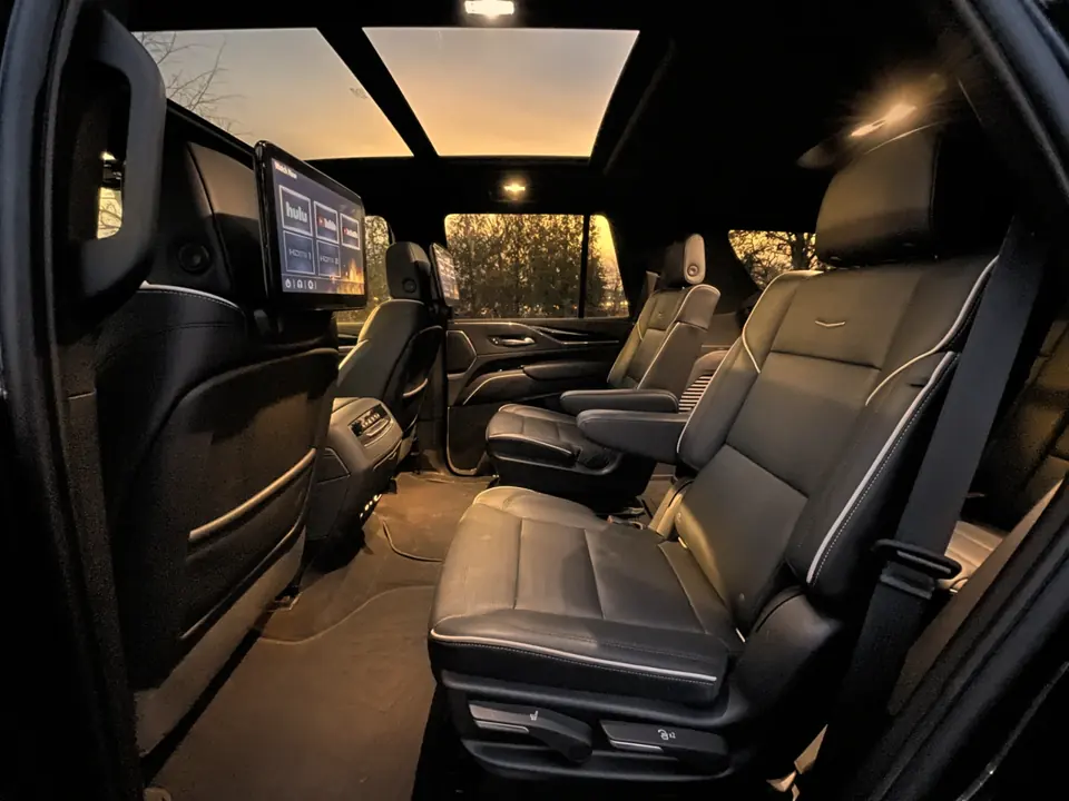The second-row captain’s chairs of an SUV at dusk, under a glass roof